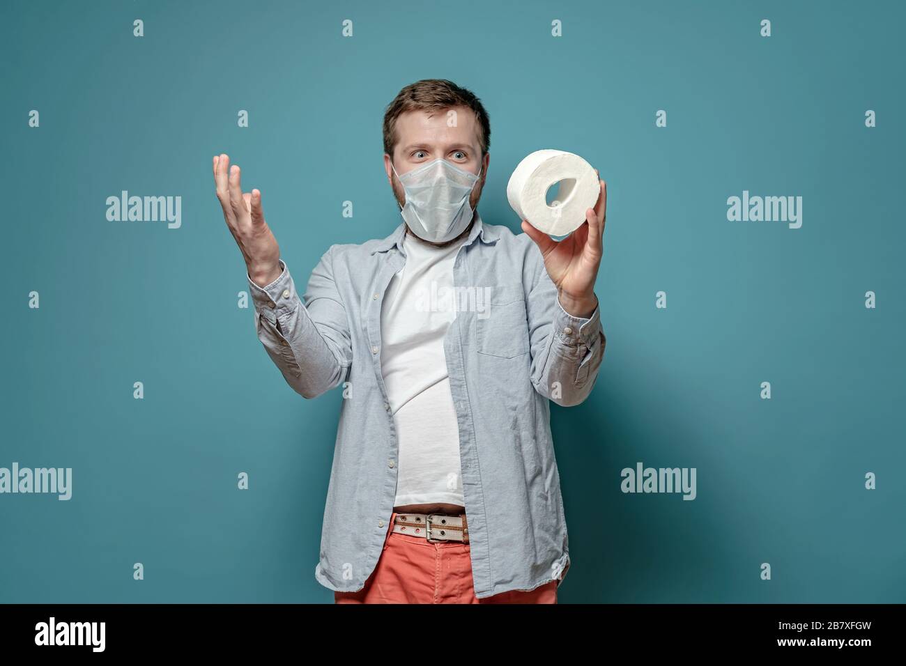 Der Mann in einer medizinischen Maske ist glücklich, er kaufte toilettenpapier während eines Gütermangels, der mit der Epidemie des Virus zusammenhängt. Paranoia. Stockfoto