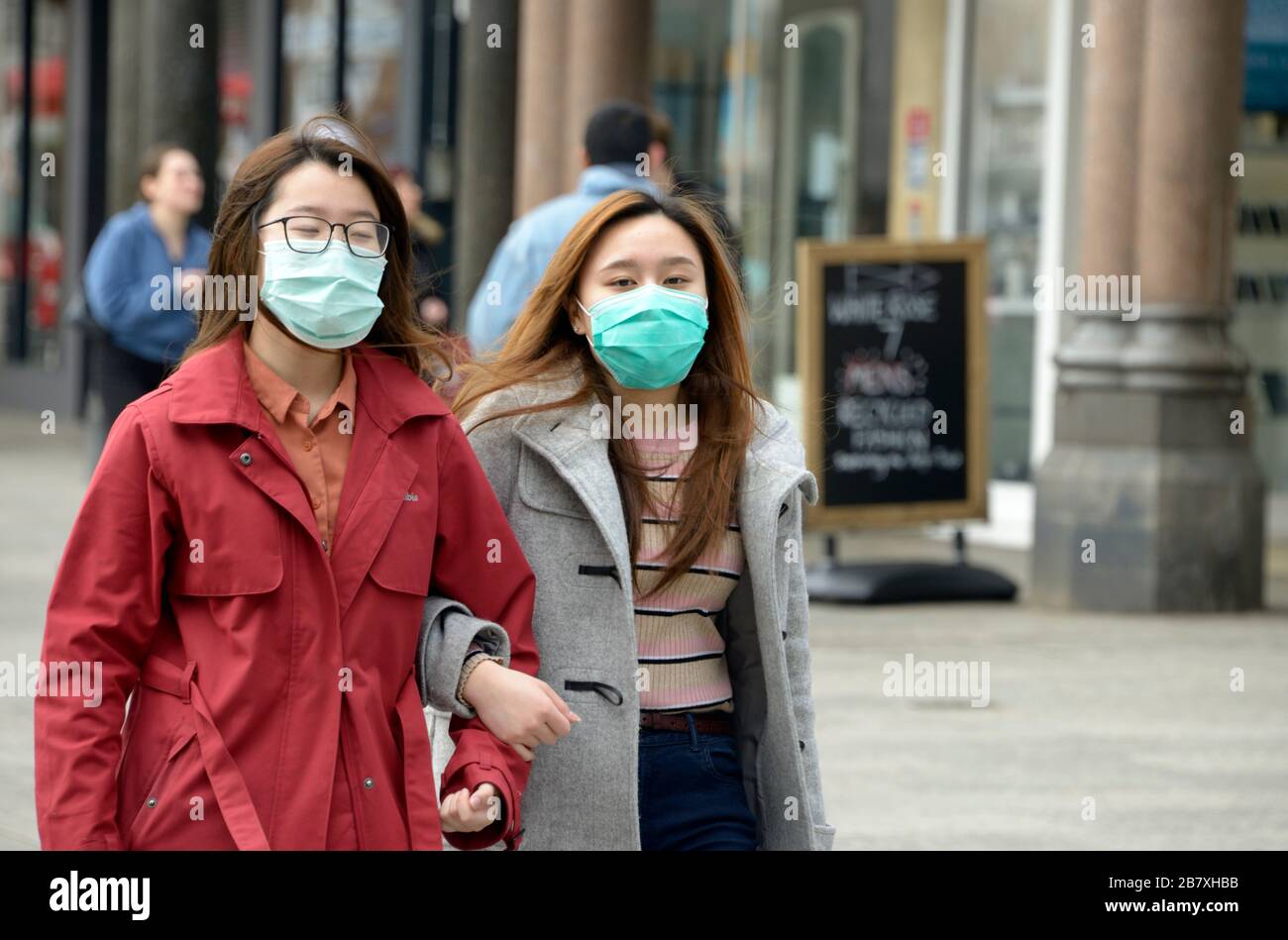 Zwei chinesische Mädchen, die beim Ausbruch des Corona-Virus in Nottingham einkaufen, Masken tragen Stockfoto