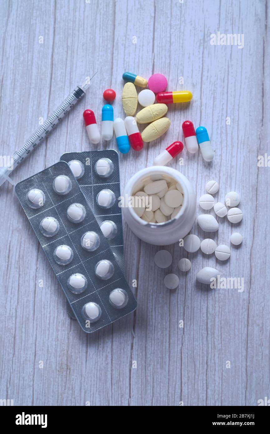 Weiße Pillen, die aus einer gestürzten weißen Pillenflasche verschüttet werden. Stockfoto