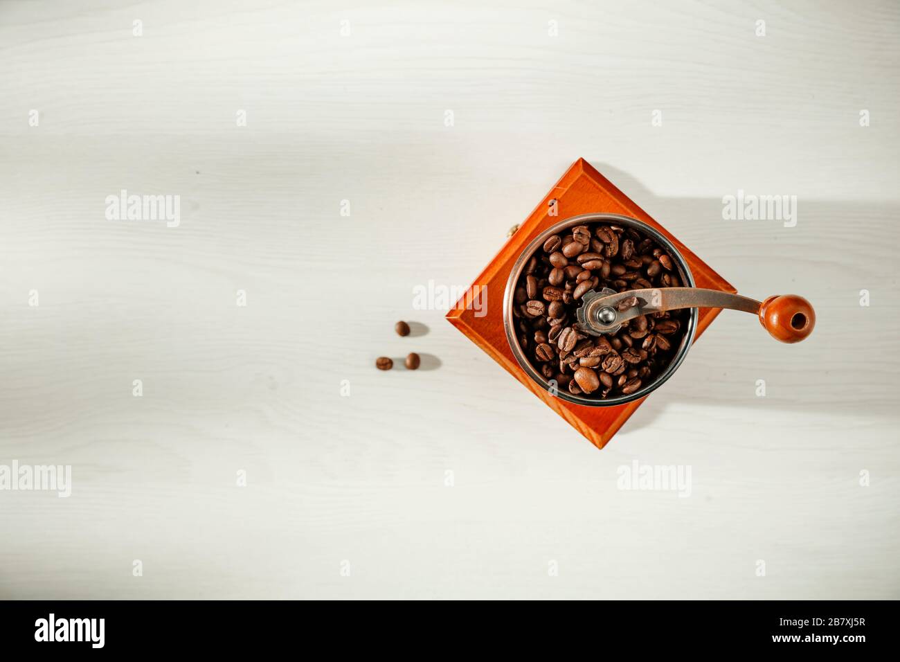 Braune Kaffeebohnen und Kaffeemühle von oben gesehen. Kaffee mit weißem Hintergrund. Kopierbereich. Platz für Werbemittel. Stockfoto