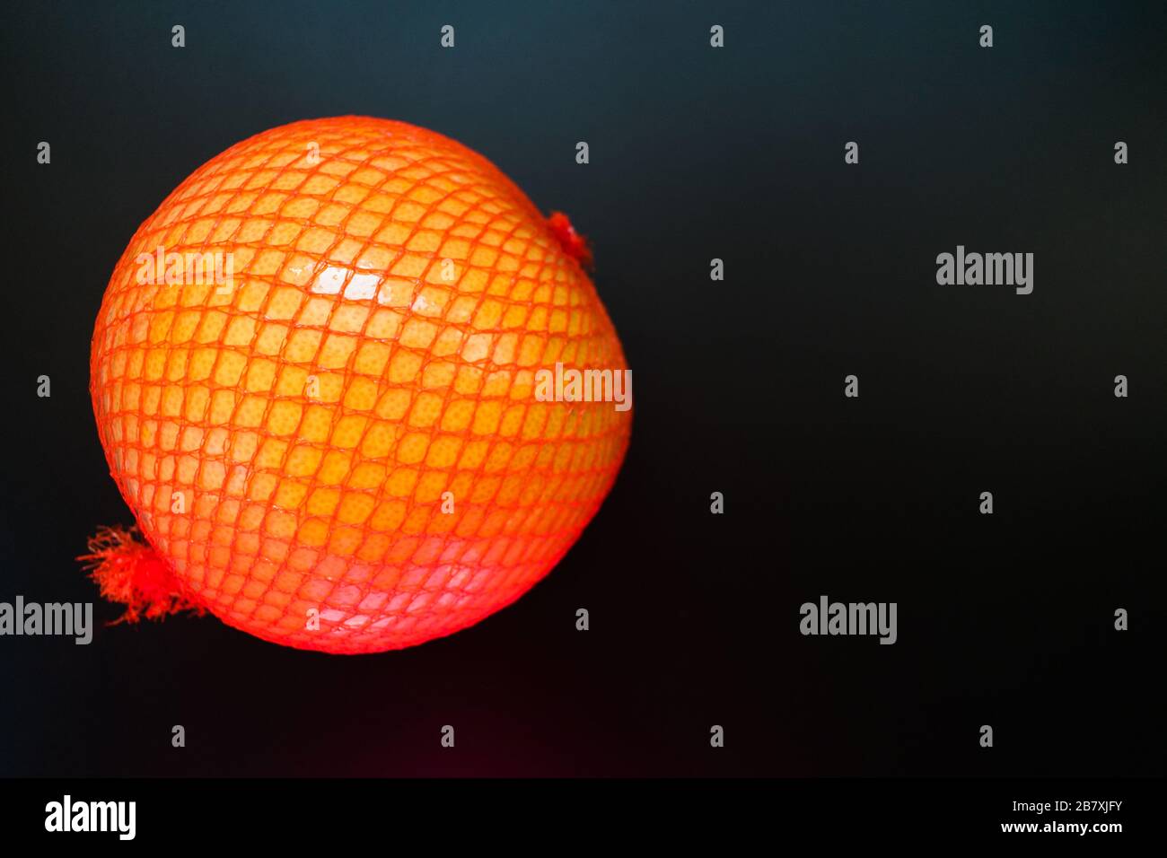 Pomelo in einem Packnetz auf schwarzem Hintergrund. Kopierbereich. Stockfoto