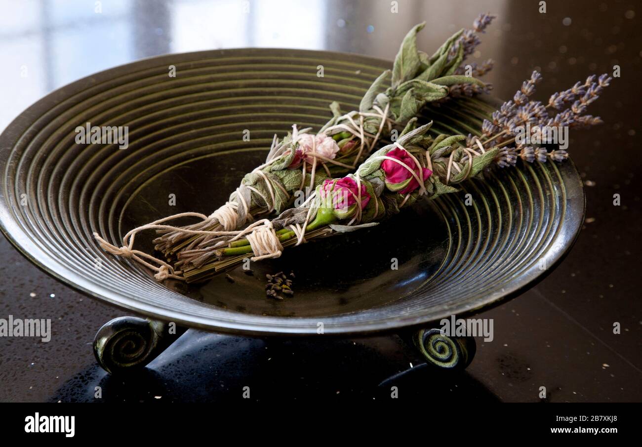 Salbei-, Rose- und Lavendelwischstöcke in brennender Schüssel Stockfoto