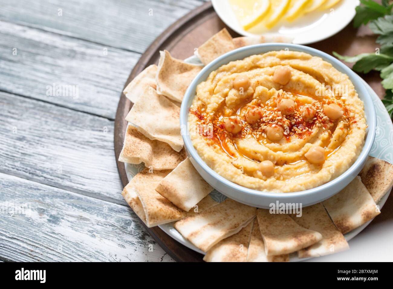 Eine Schüssel cremig hausgemachter Hummus mit Olivenöl und Pita Pommes. Traditionelle vegane gesunde Mahlzeit. Stockfoto