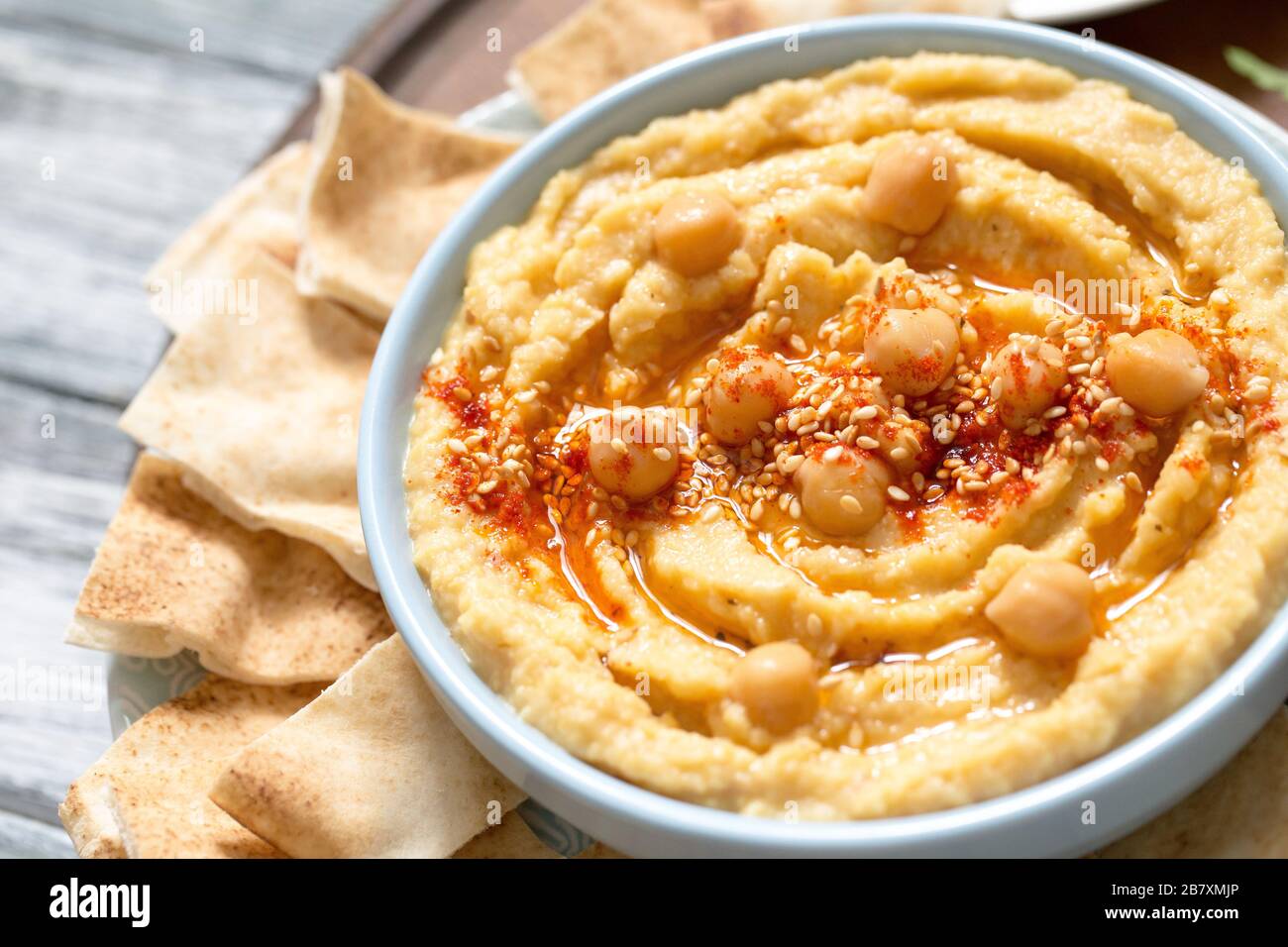 Eine Schüssel cremig hausgemachter Hummus mit Olivenöl und Pita Pommes. Traditionelle vegane gesunde Mahlzeit. Stockfoto