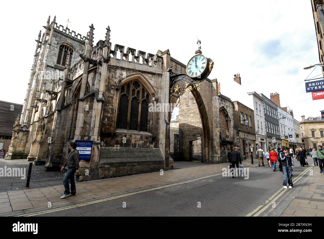 Eine große runde Uhr (1856) mit einer ornamentalen Wandstütze über dem Bogen bei St. Martin Le Grand, einer Pfarrkirche in der Coney Street, York, Großbritannien. Ein Stockfoto