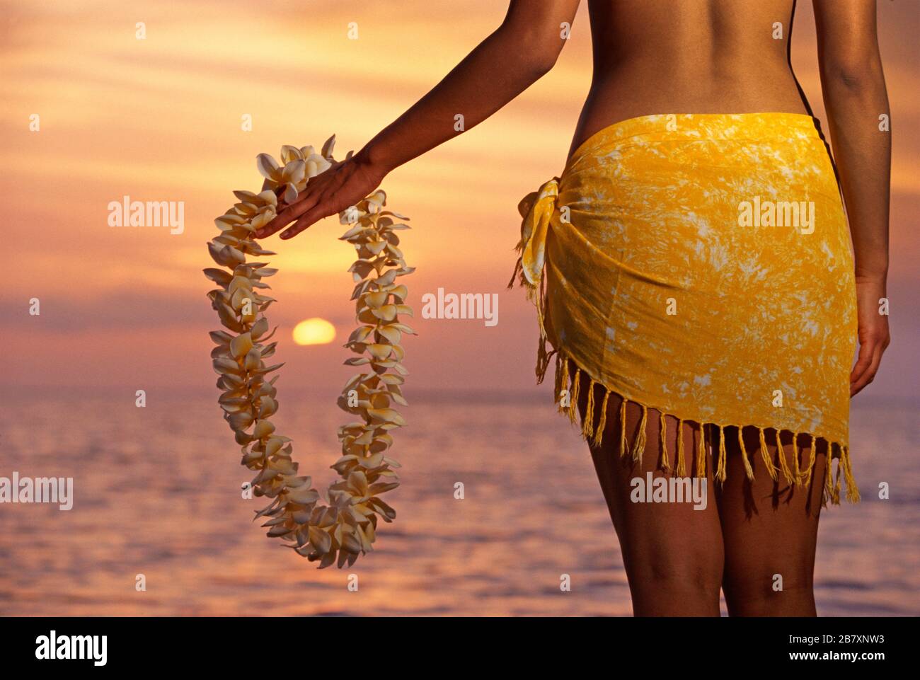 Hawaiianische Frau, die bei Sonnenuntergang in Lahaina, Maui, Hawaii ein Klempnerei hält. Stockfoto