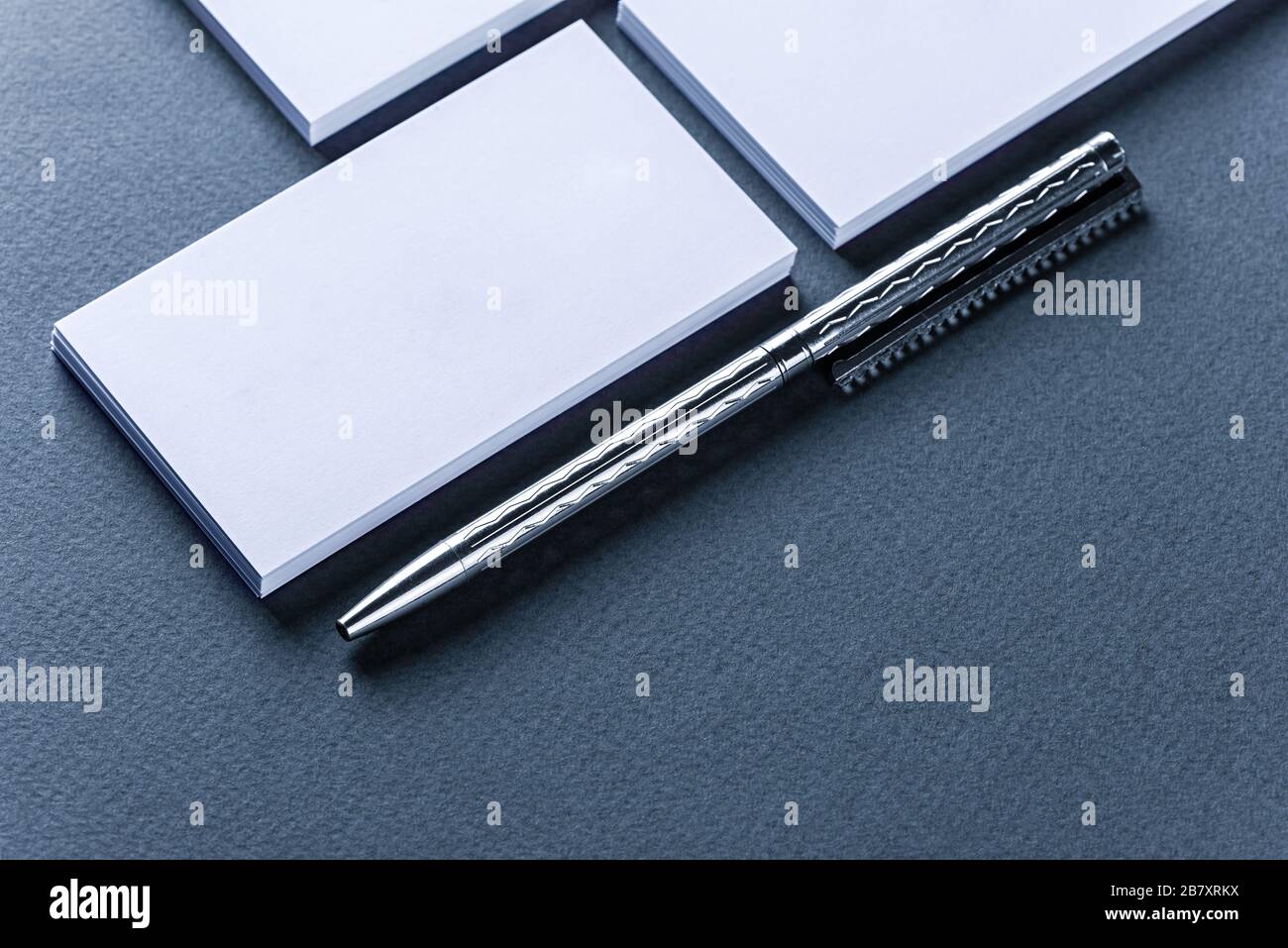 Verspottung von Visitenkartenstapeln in Reihen und Stift auf blauem Hintergrund. Stockfoto