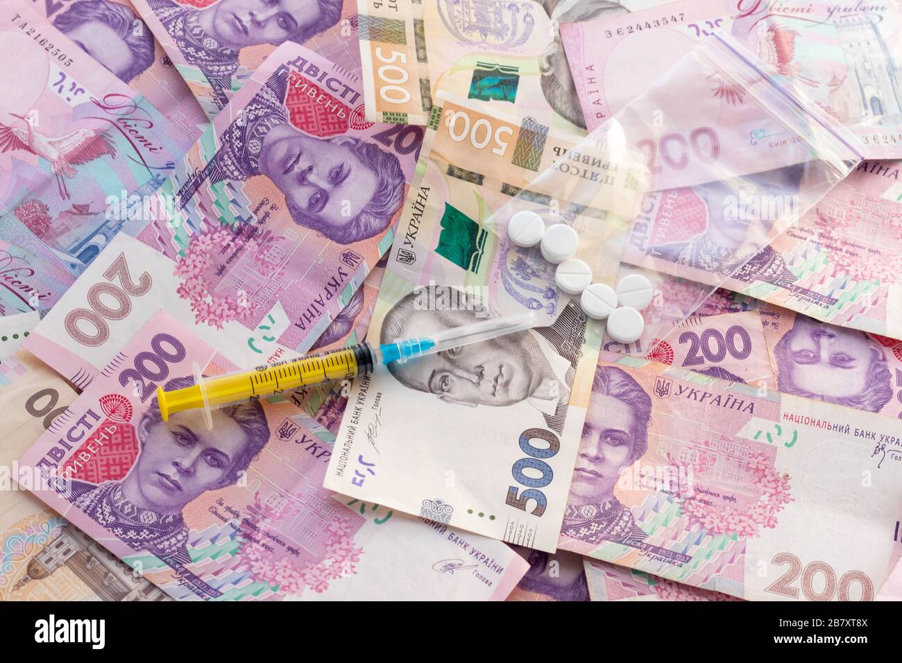 Spritze auf dem Stapel ukrainischer Banknoten. Verkauf von Drogen, Ocain, Heroin oder Ecstasy. Illegales Geschäft. Konzept für das Gesundheitswesen und die Medizin. Stockfoto