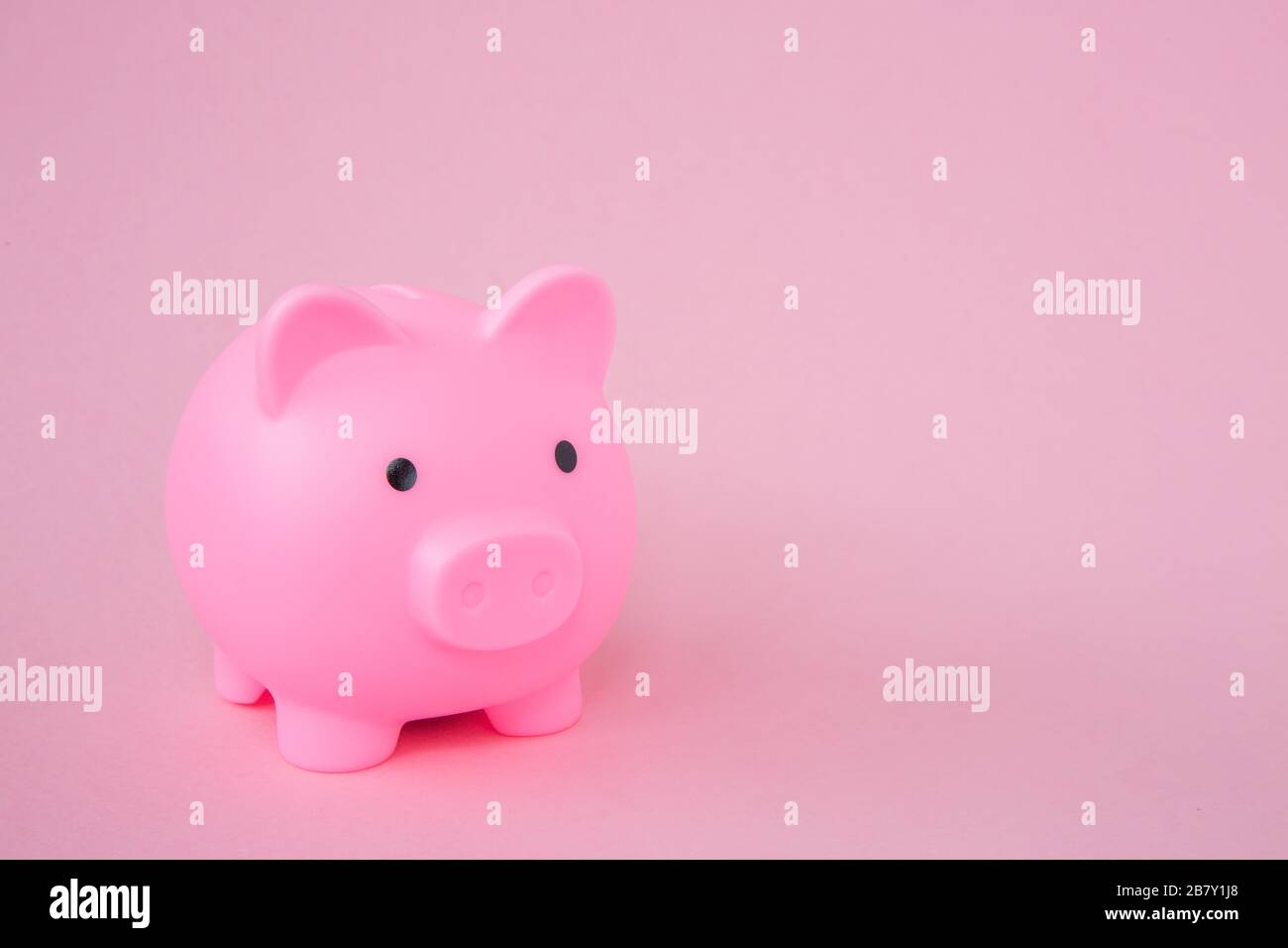 Eine pinkfarbene Kids Piggy Bank auf pinkfarbenem Hintergrund mit Platz für Kopien in einem Hintergrundbild zum Sparkonzept Stockfoto