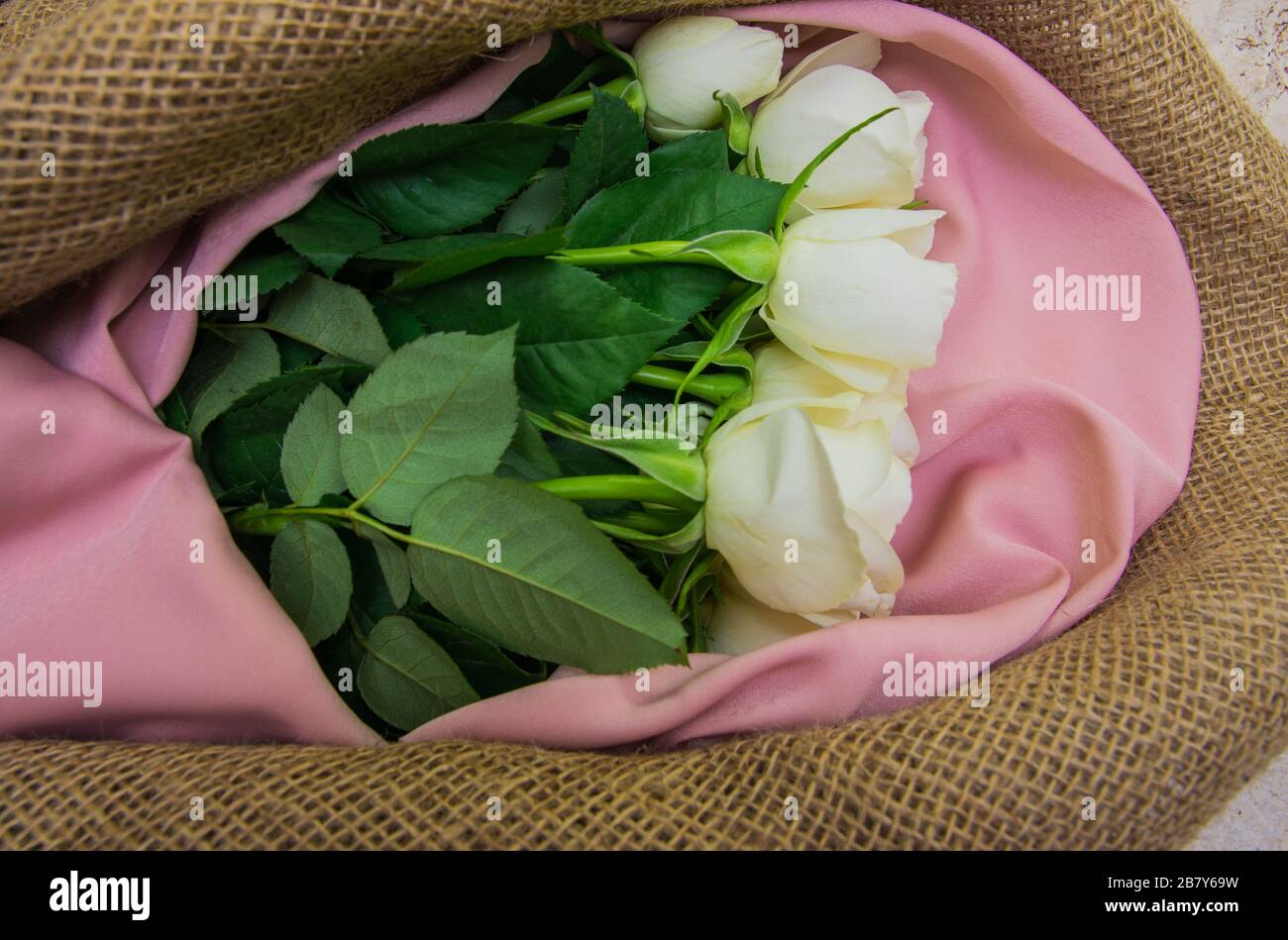 Weißer Rosenstrauß auf dem Naturstoff-Wickelpapier. Frühlingsblumen auf dem Korkhintergrund . Draufsicht mit Platz für Text. Kopierbereich. Stockfoto