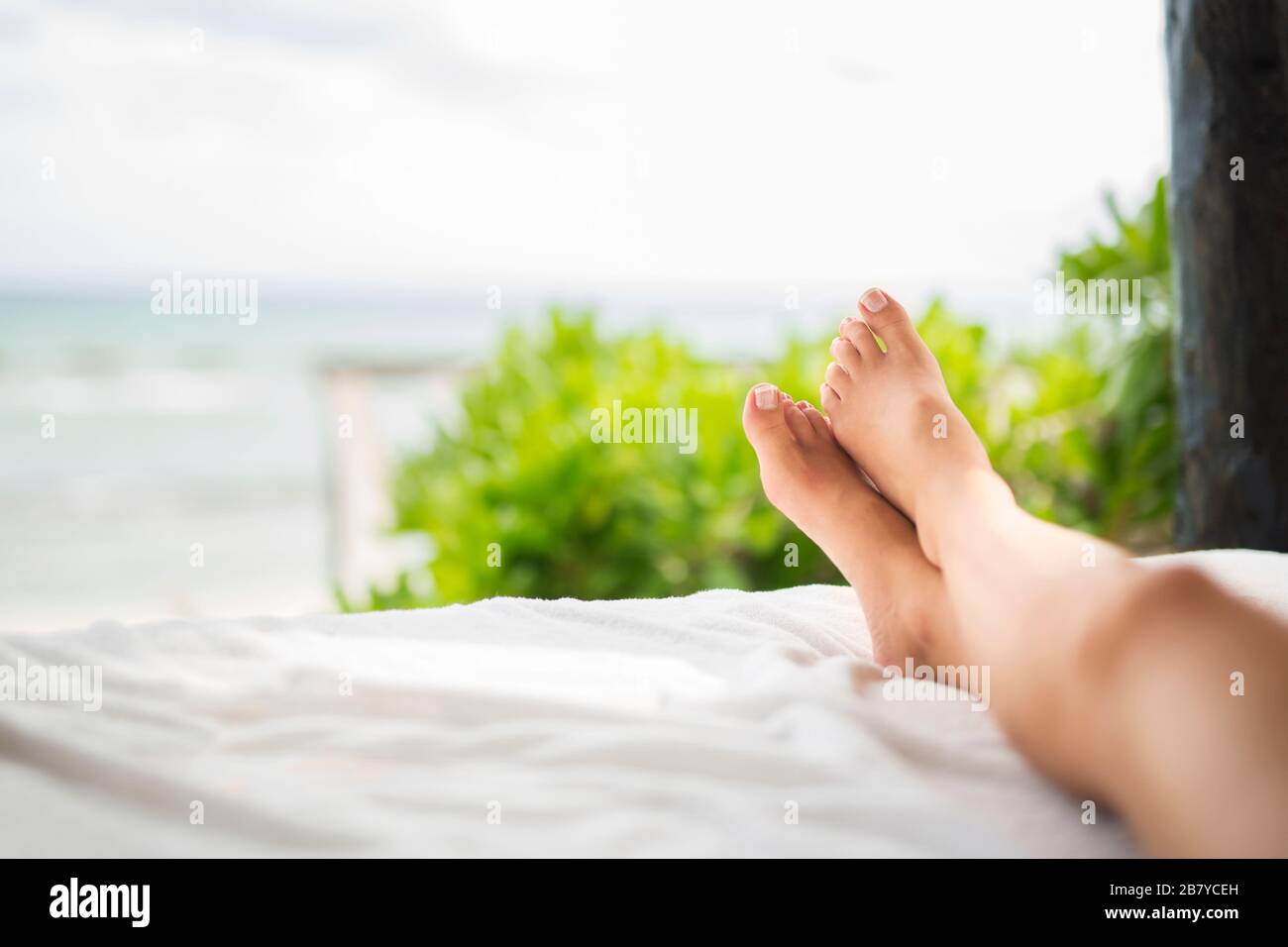 Die Beine der Frau sonnen sich in der Nähe eines Ozeanstrands Stockfoto