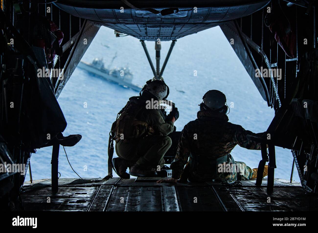 SOUTH CHINA SEA (15. März 2020) Marines mit 31. Marine Expeditionary Unit (MEU) sehen Sie sich den geführten Raketenkreuzer der Ticonderoga-Klasse USS Bunker Hill (CG 52) von der Rückseite eines Super Stallion Helikopters CH-53E mit Marine Medium Tiltrotor Squadron (VMM) 265 (verstärkt), 31. MEU, Nach dem Abflug des amphibischen Angriffsschiffs USS America (LHA 6) während eines simulierten Besuchs, Bord, Suche und Beschlagnahme der CG 52. Als Expeditionary Strike Force integriert das Navy-Marine-Corps-Team die Kampfkraft der Theodore Roosevelt Carrier Strike Group mit der flexiblen Fähigkeit der amerikanischen Stockfoto