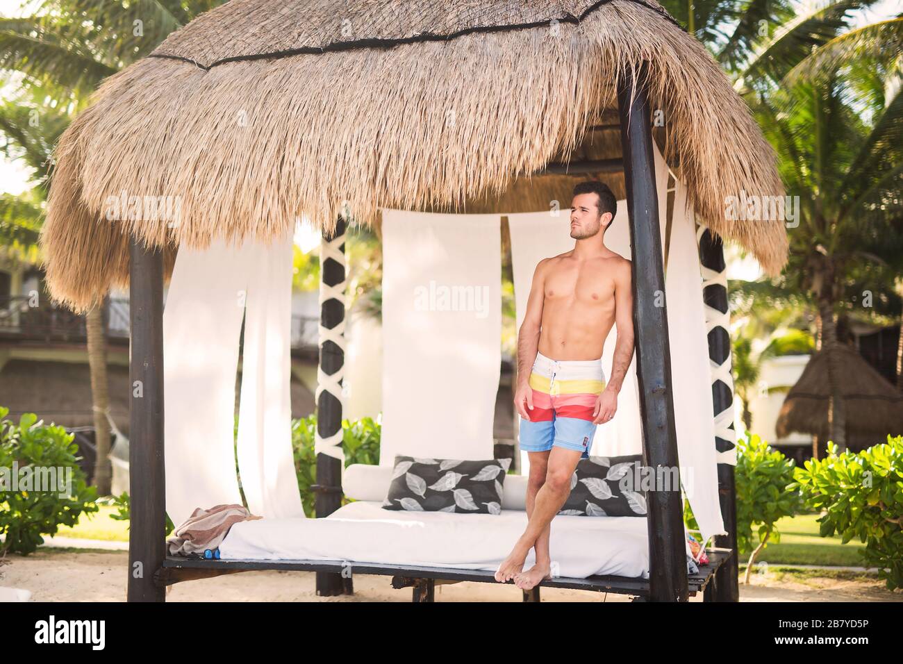 Genießen Sie die warme Sonne am mexikanischen Strand - junger Mann, der im Schatten ruht Stockfoto