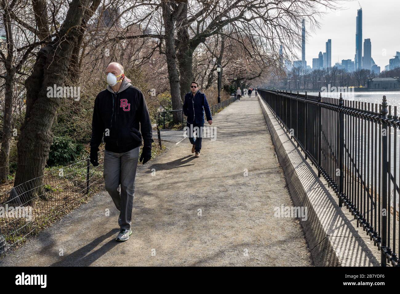 New York, USA, 18. März 2020. Die Menschen benutzen Gesichtsmasken und halten die "soziale Distanzierung" beim gehen in New York City neben dem Central Park Reservoir Stockfoto
