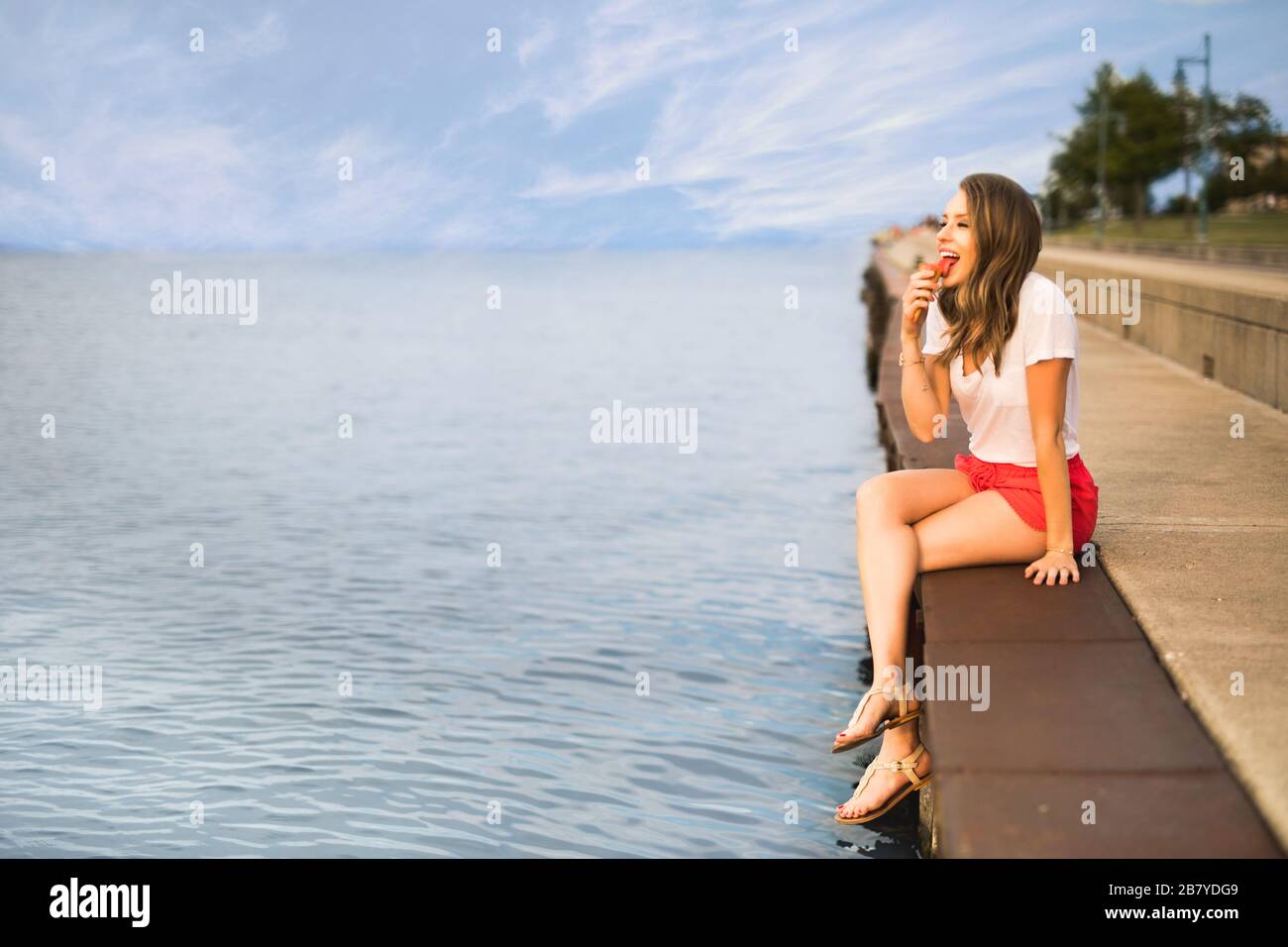 Junge Frau leckt an einem Sommerabend einen Eiskegel Stockfoto