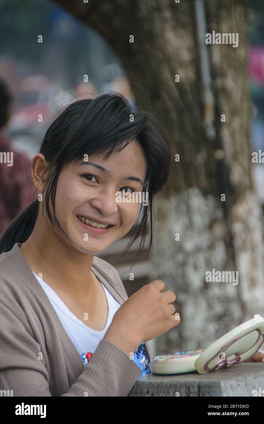 Guilin, China - 11. Mai 2010: Stadtzentrum. Junge Frau lächelt und macht ihr Make-up draußen entlang des Li-Flusses. Stockfoto