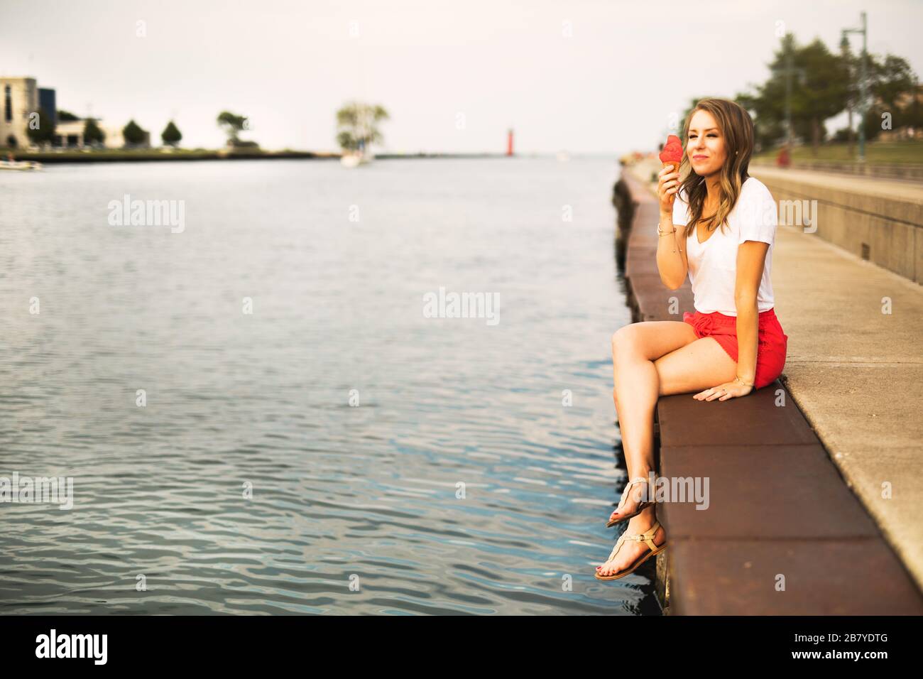 Junge Frau leckt an einem Sommerabend einen Eiskegel Stockfoto