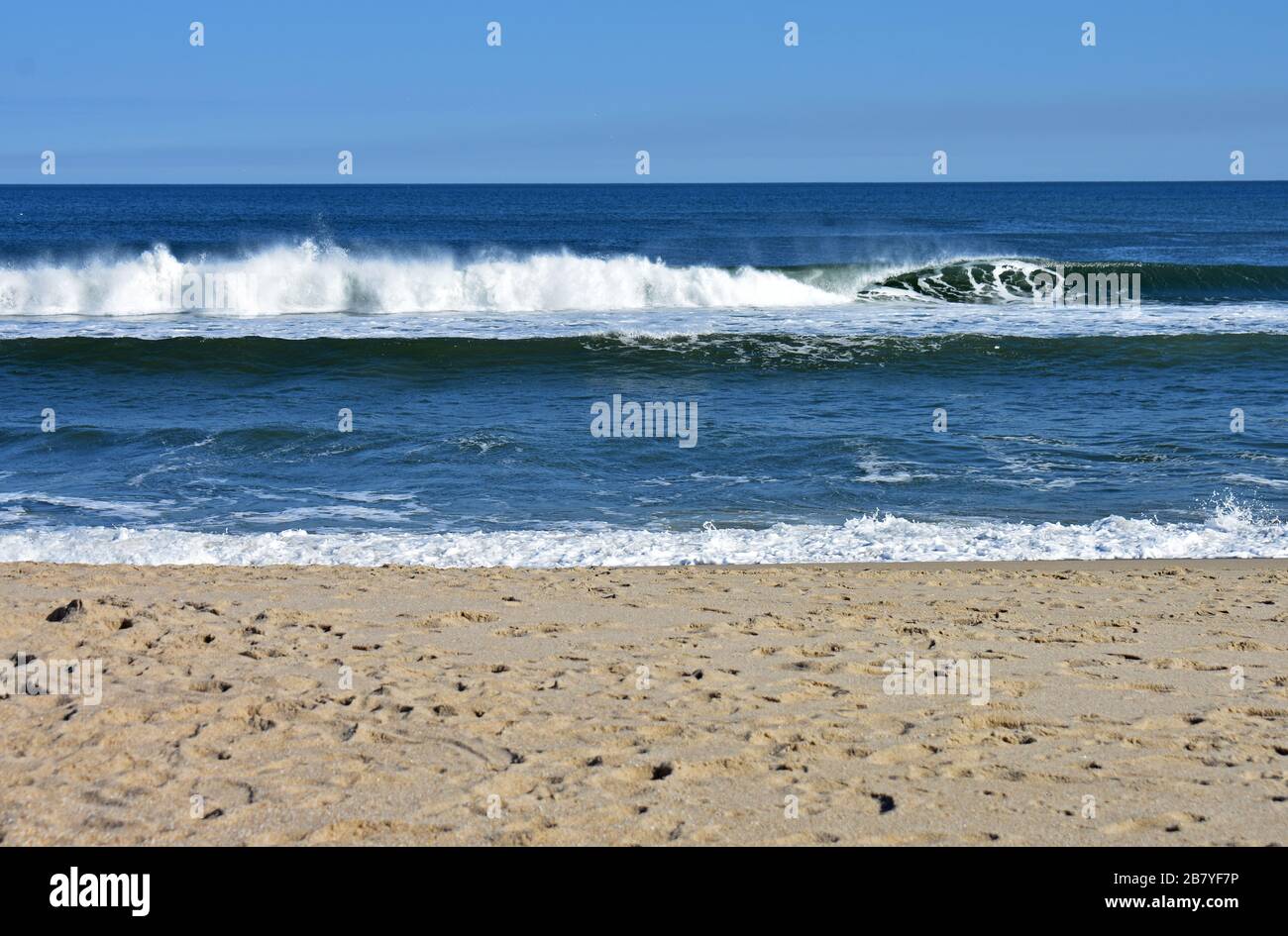 Leichte Winde vom Ozean führen dazu, dass Wellen an einem sandigen Haken, New Jersey, Strand ins Ufer stürzen Stockfoto