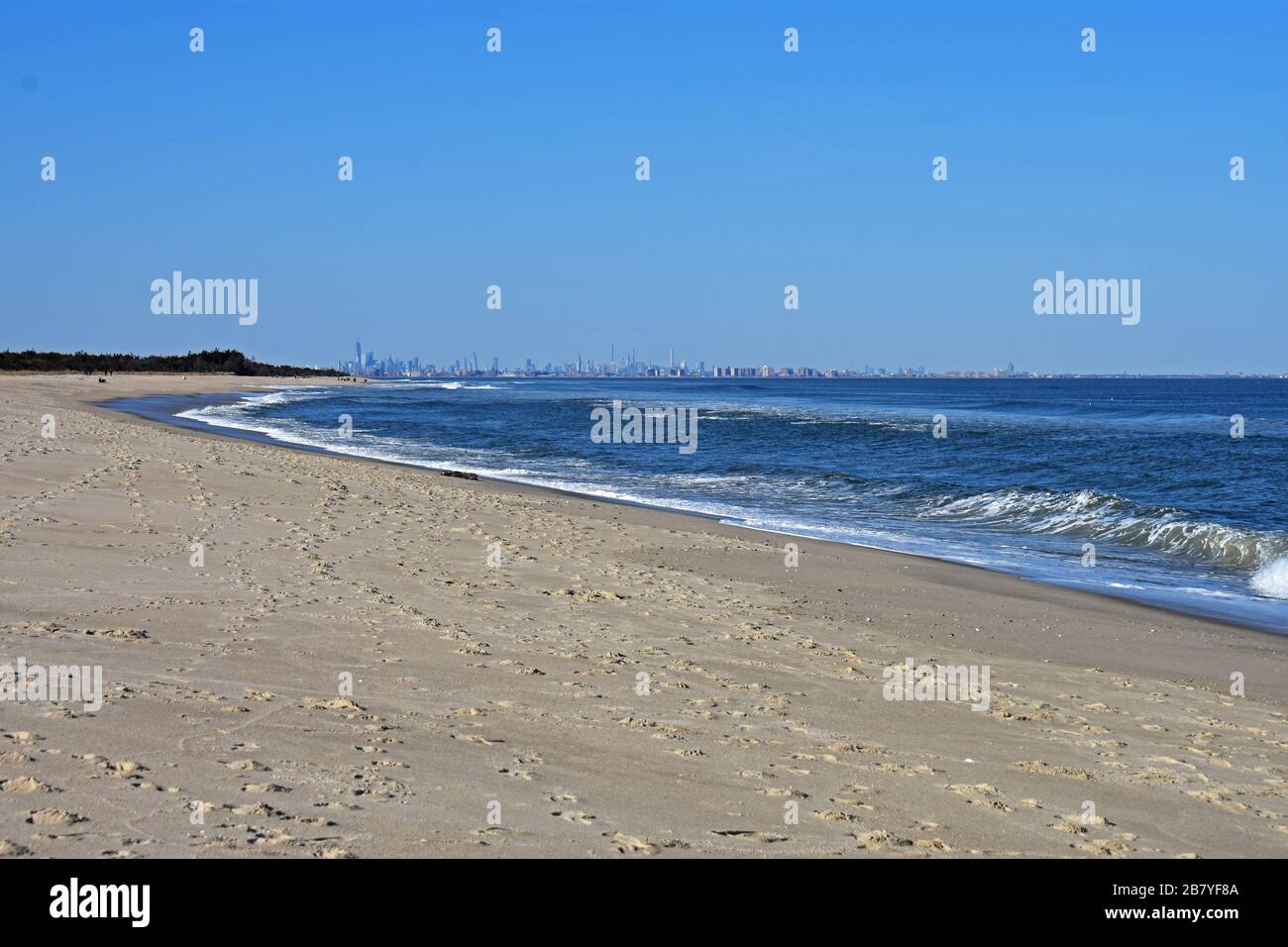 Leichte Winde vom Ozean führen dazu, dass Wellen an einem sandigen Haken, New Jersey, Strand ins Ufer stürzen Stockfoto