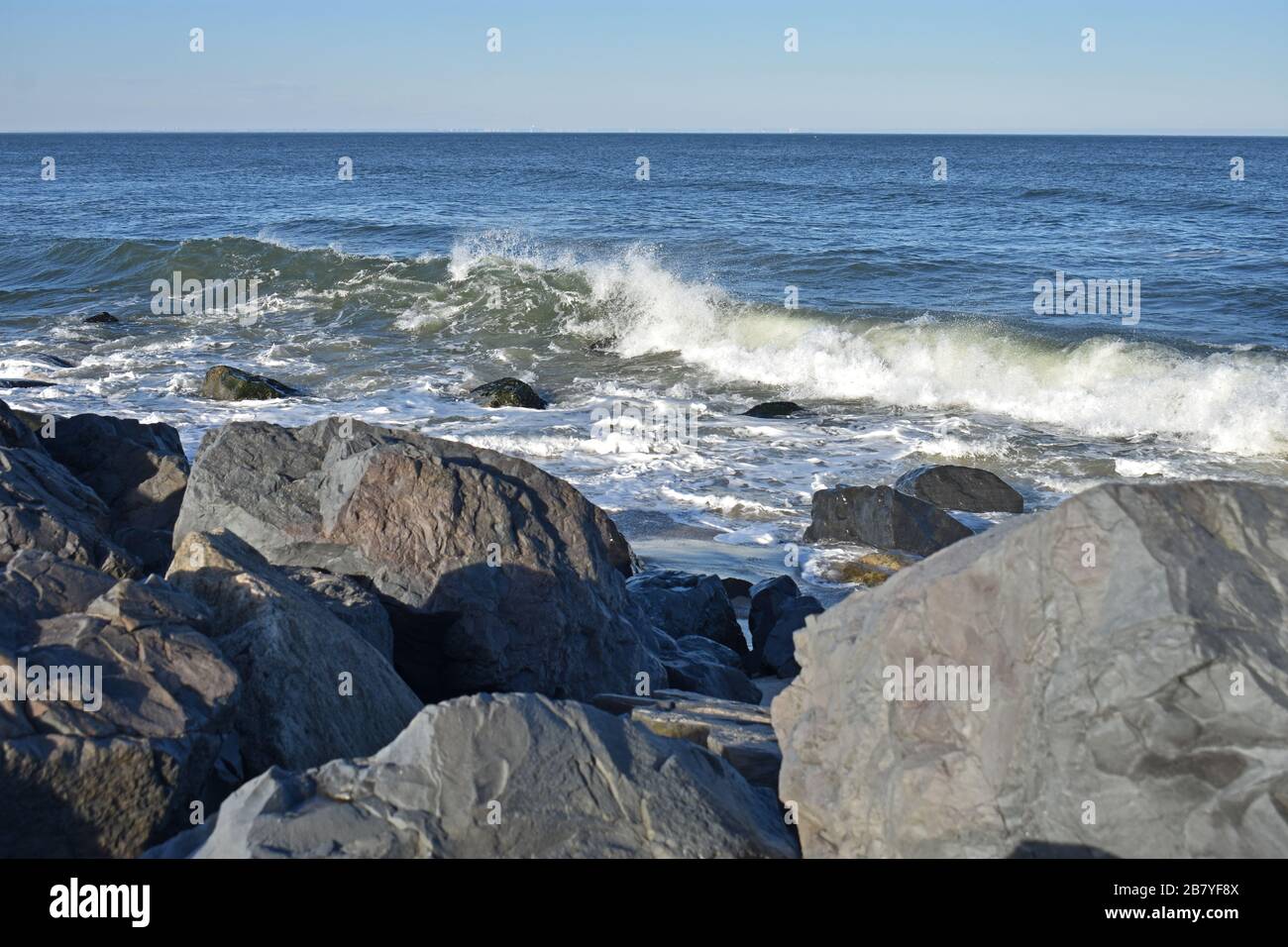 Leichte Winde vom Ozean führen dazu, dass Wellen an einem sandigen Haken, New Jersey, Strand ins Ufer stürzen Stockfoto