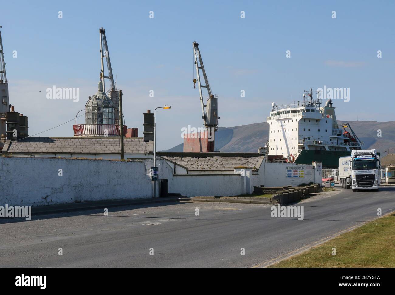 Hafenkräne und Tanker im Hafen von Greenore, County Louth, Ostküste Irlands, während ein Schwerlastfahrzeug den irischen Tiefwasserhafen verlässt. Stockfoto