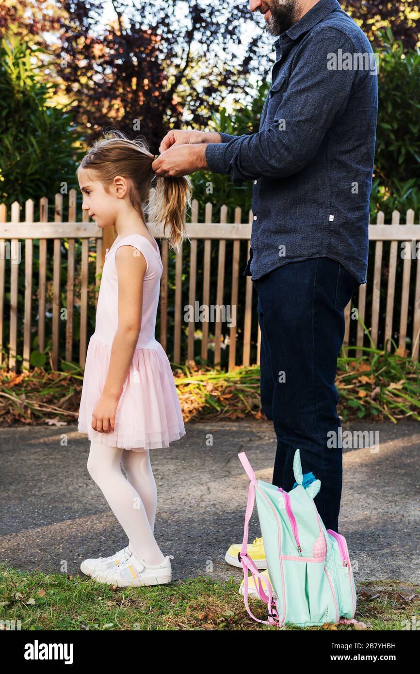 Mann bindet die Haare seiner Tochter in Pferdeschwanz Stockfoto
