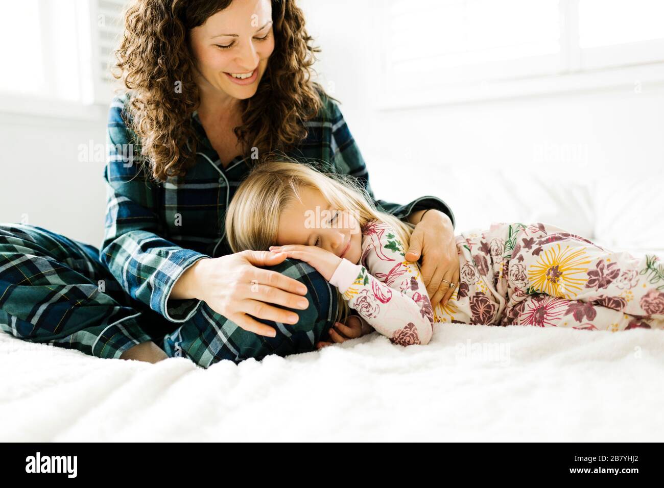 Mutter und Tochter umarmt auf Bett Stockfoto