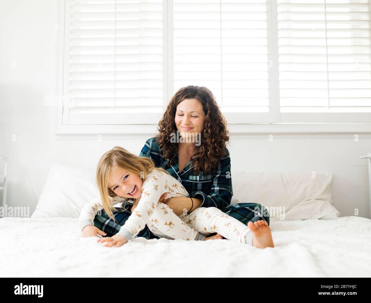 Mutter und Tochter umarmt auf Bett Stockfoto