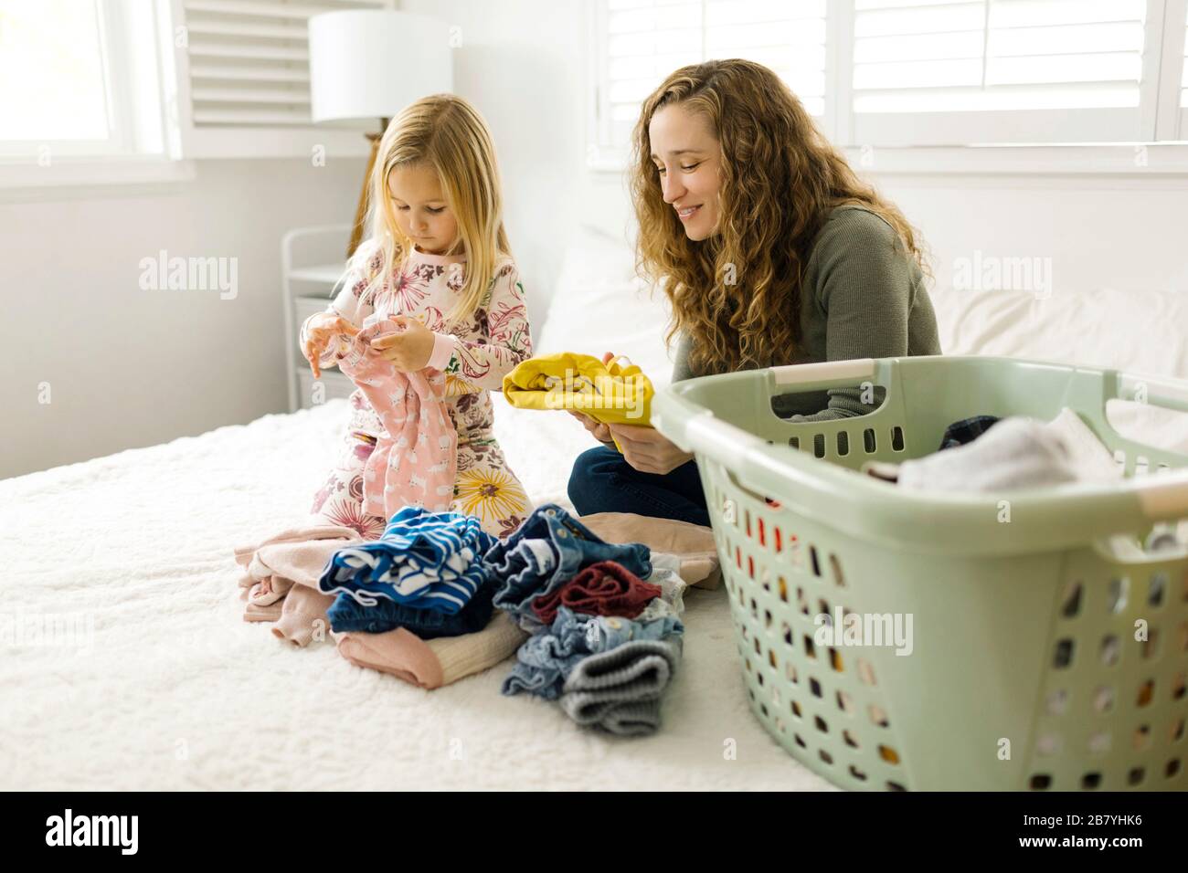 Mutter und Tochter faltende Wäsche auf dem Bett Stockfoto