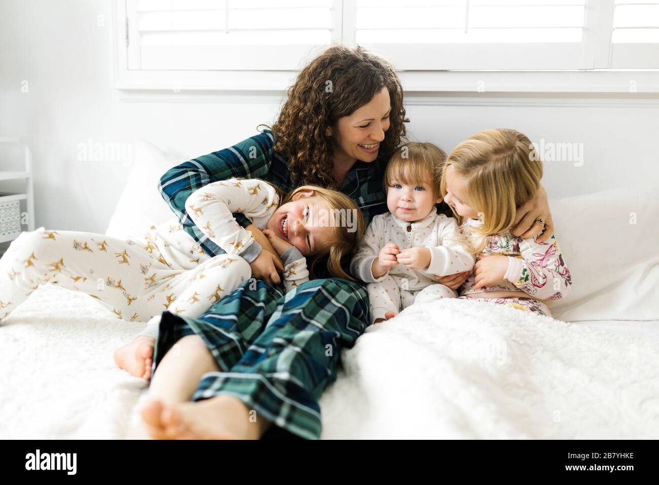 Frau, die mit ihren Töchtern auf dem Bett sitzt Stockfoto