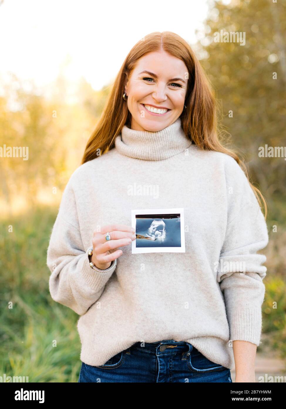 Lächelnde schwangere Frau hält Ultraschall-Foto Stockfoto