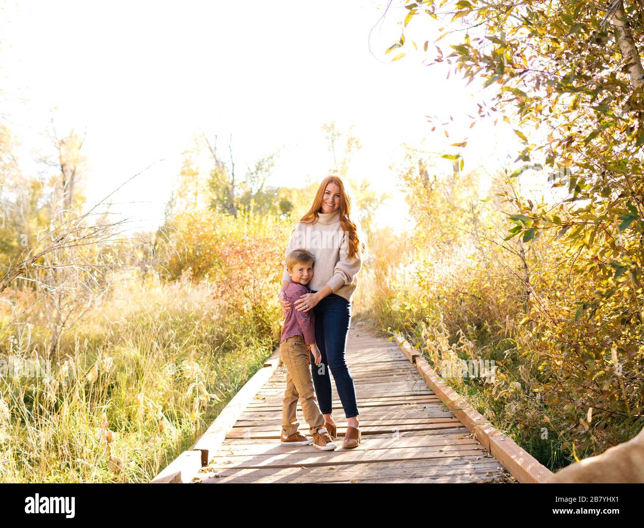 Mutter und Sohn umarmen auf Waldpromenade Stockfoto
