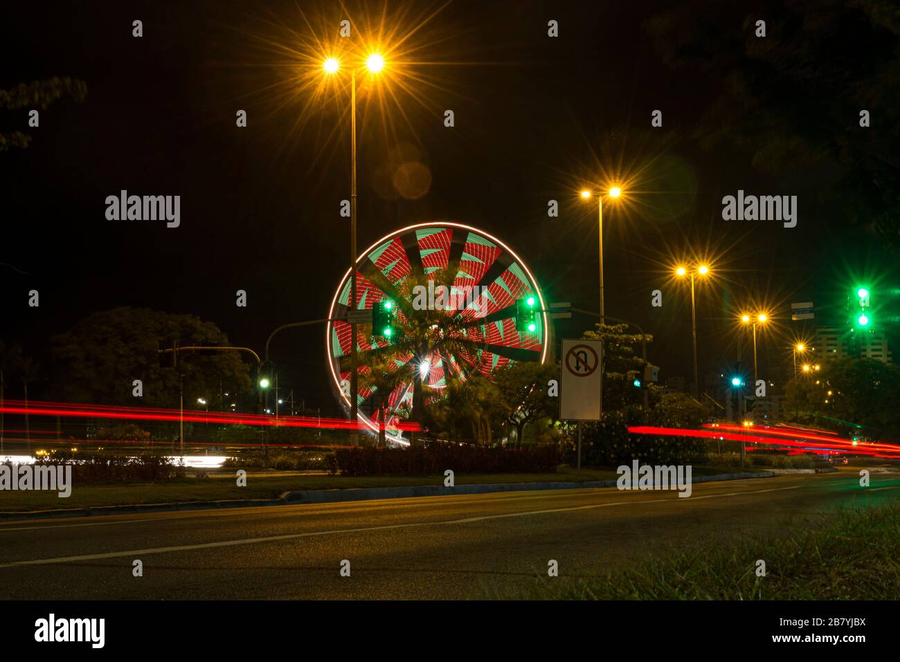 Lange Belichtung von bunten Riesenrad- und Lichtwegen auf der Schnellstraße in der Nacht. Zeiterscheinung der Ampeln auf der Allee in Florianopolis. C Stockfoto