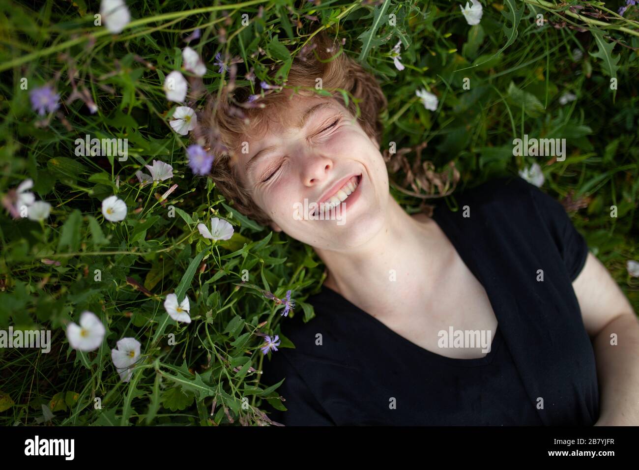Lächelnde junge Frau, die im Gras liegt Stockfoto