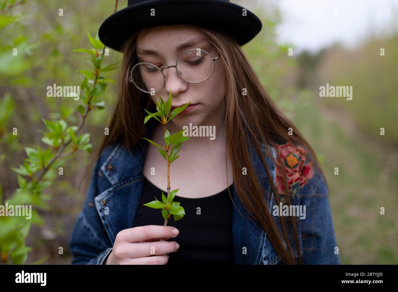 Junge Frau riecht Blätter auf Zweig Stockfoto