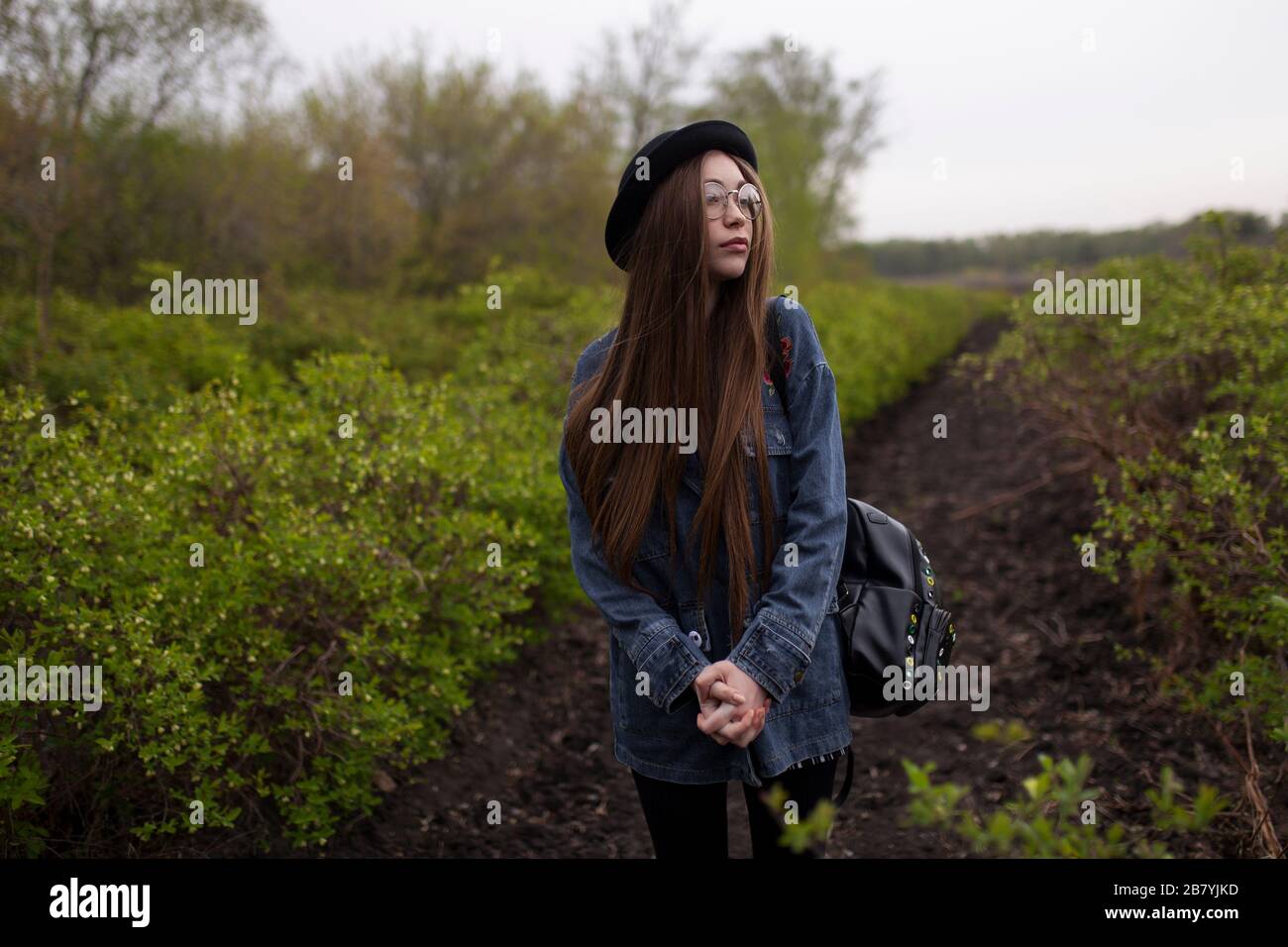 Junge Frau mit Jeansjacke im Feld stehend Stockfoto