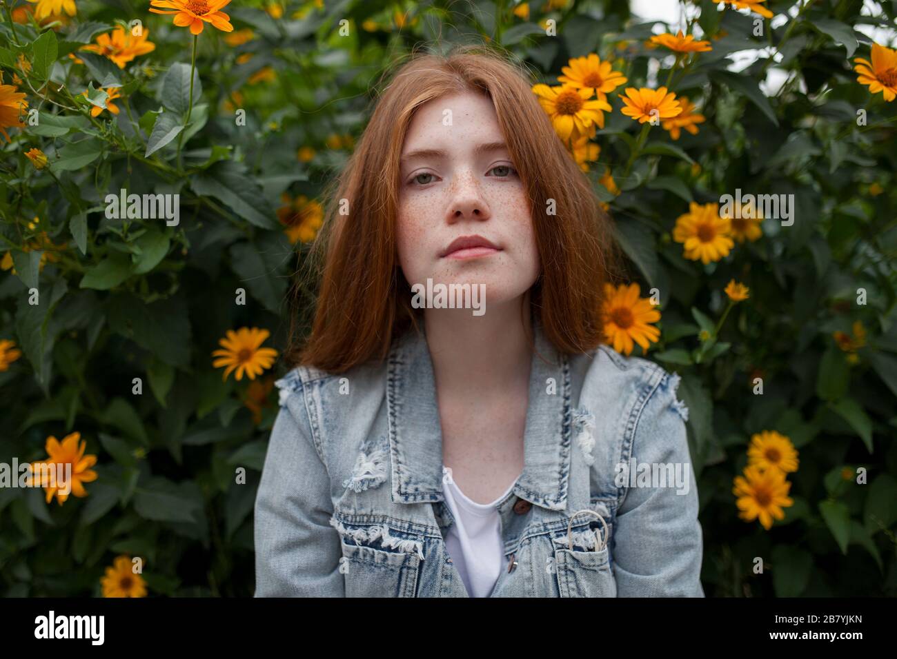 Teenager Mädchen durch Busch mit orangen Blumen Stockfoto