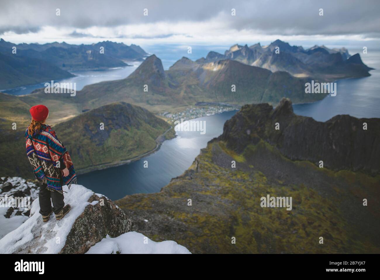 Junge Frau in rotem Hut und Pullover auf verschneiten Berg Stockfoto