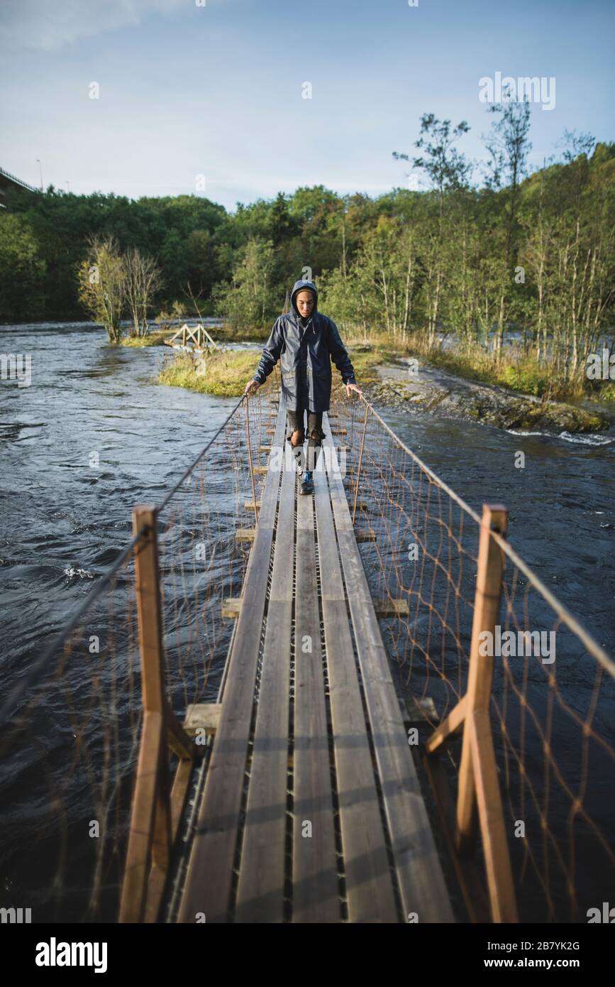 Junger Mann, der über eine Holzbrücke geht Stockfoto