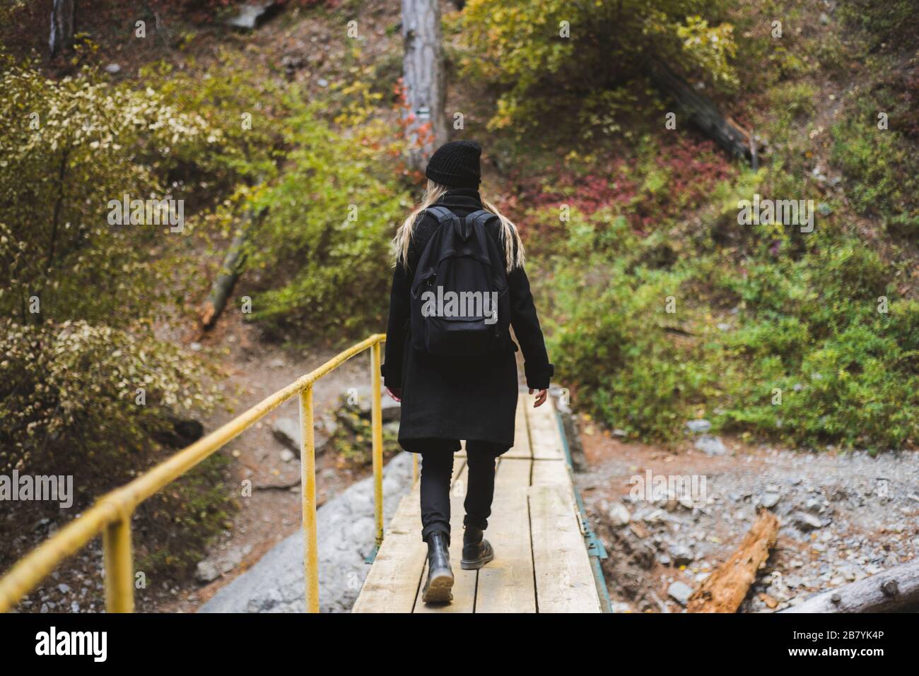 Junge Frau, die im Wald über die Brücke läuft Stockfoto