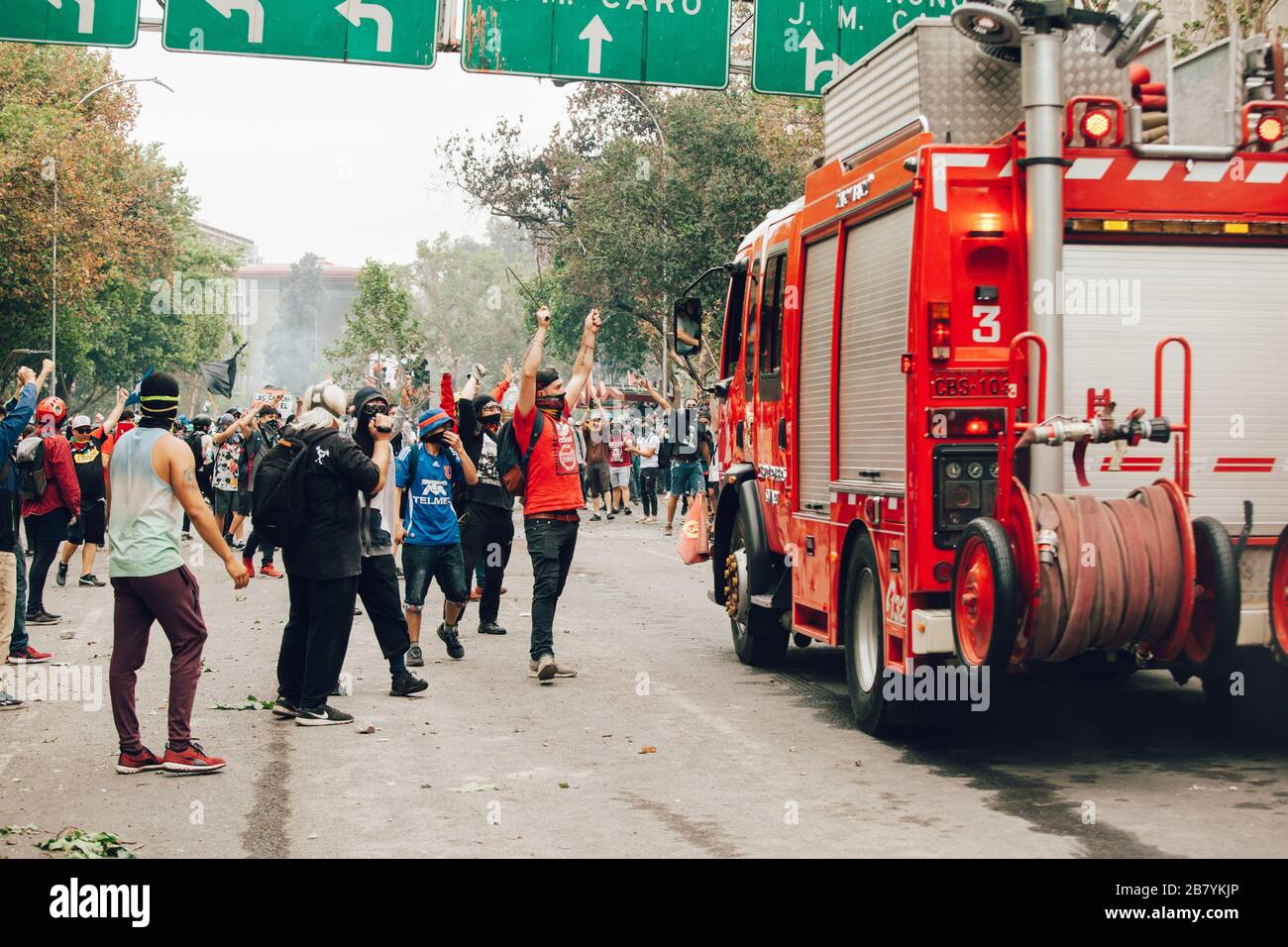 SANTIAGO, CHILE - 8. NOVEMBER 2019 - Demonstranten ziehen Barrikaden, um während der Proteste gegen die Regierung Pinera für die n eine Autofeuerpumpe zu passieren Stockfoto