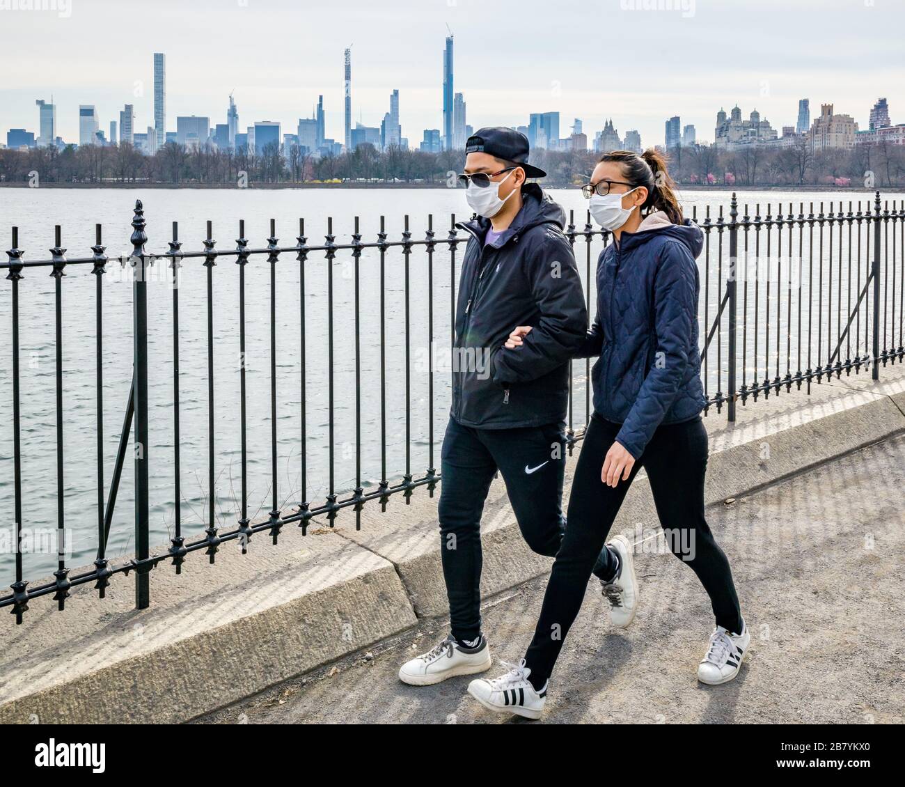 New York, USA, 18. März 2020. Während der Coronavirus-Krise tragen die Menschen Gesichtsmasken, während sie neben dem Central Park Reservoir in der Stadt New York spazieren gehen. Stockfoto