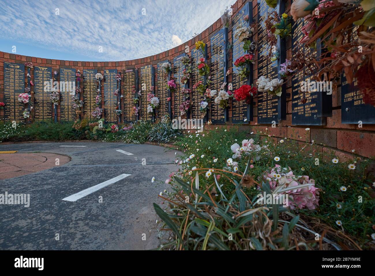 Die Mauer aus Backstein, Blumen und Namen auf der Australian Truck Drivers Memorial Wall. In Tarcutta, New South Wales, Australien. Stockfoto