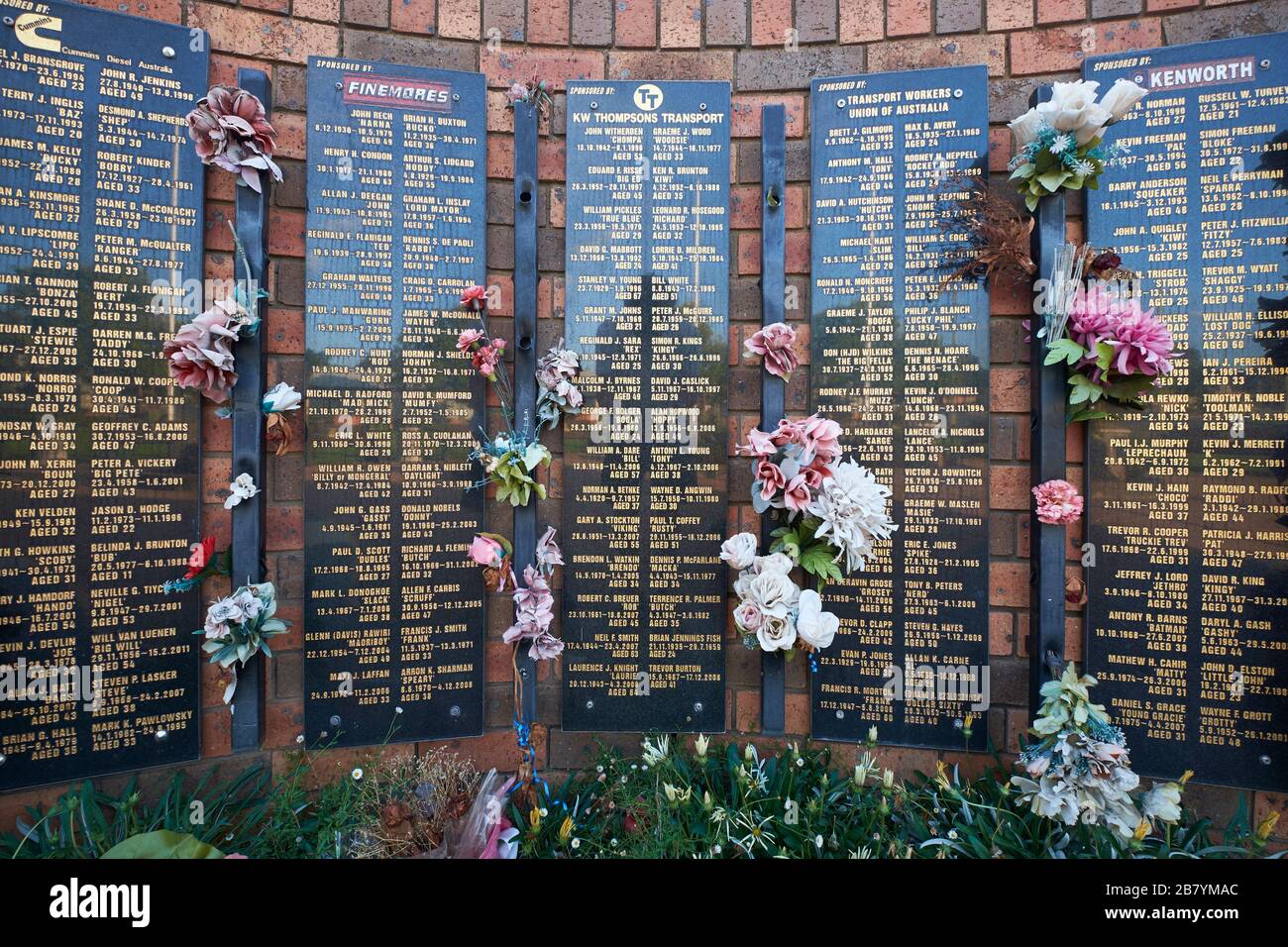 Die Mauer aus Backstein, Blumen und Namen auf der Australian Truck Drivers Memorial Wall. In Tarcutta, New South Wales, Australien. Stockfoto