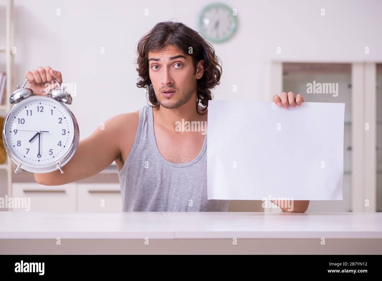 Junger Mann, der zu Hause leeres Papier hält Stockfoto