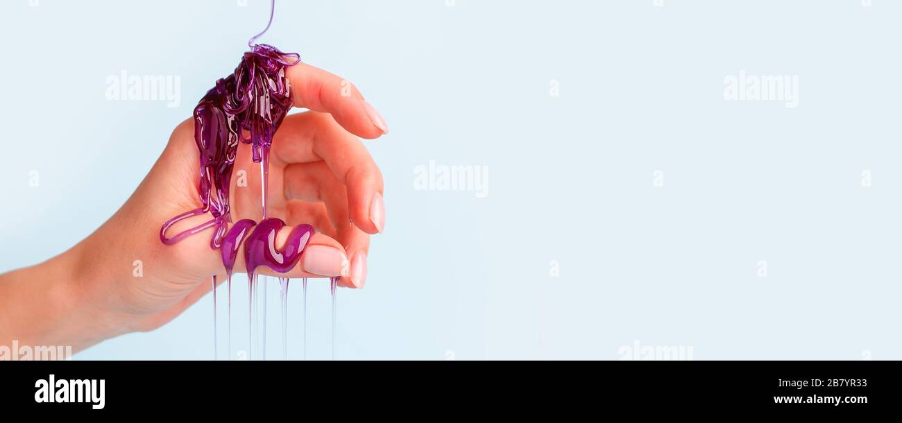 Süße Karamellpaste für die violette Farbe an der weiblichen Hand, Touch Sensative kreative Idee, Haarentfernungskonzept, Kosmetikindustrie, Banner-Flyer c Stockfoto