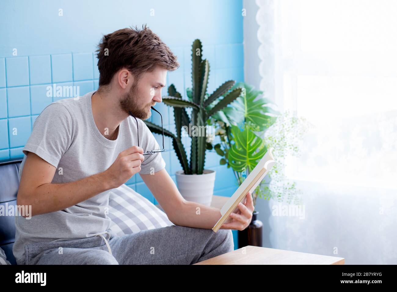 Junger Mann Buch auf dem Sofa im Wohnzimmer. Stockfoto