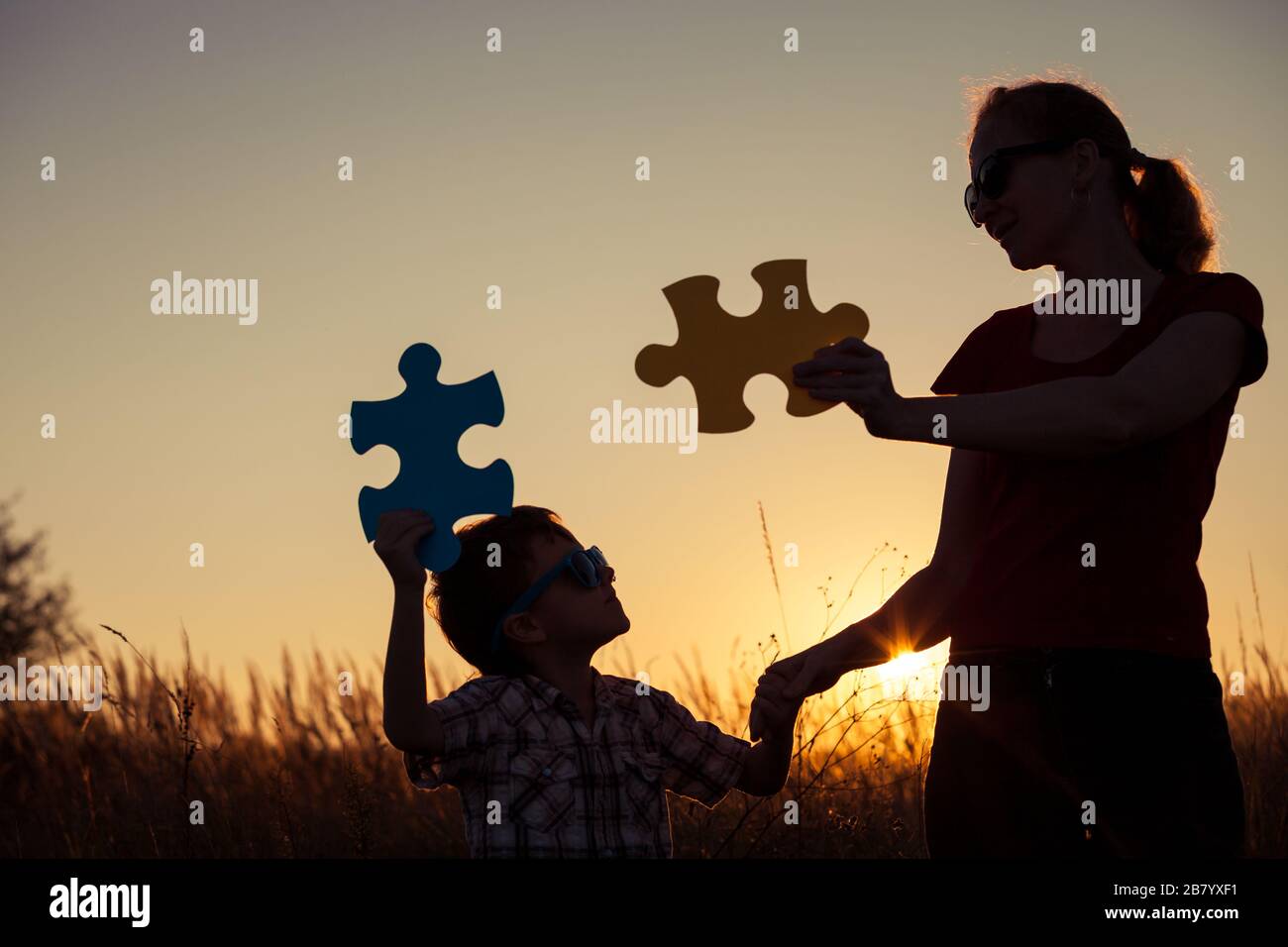Mutter und Sohn spielen zum Sonnenuntergang im Park. Leute, die Spaß auf dem Feld haben. Das Konzept des Kindes ist bereit zur Schule zu gehen. Stockfoto