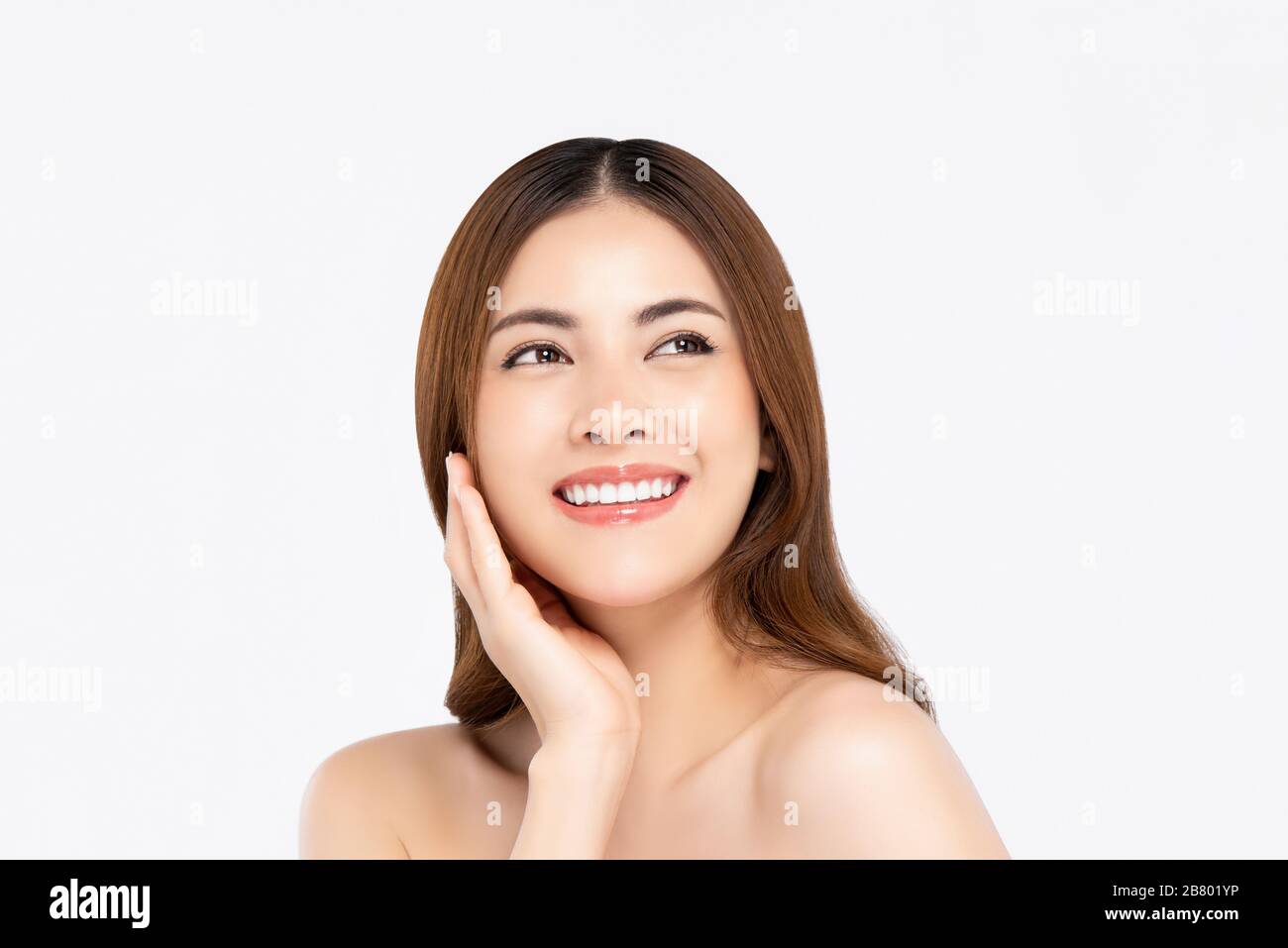 Fröhliche, schön lächelnde asiatische Frau mit klarer fairer Haut, die Hand berührt, während sie in weiß isoliertem Hintergrund aufblickt Stockfoto Fröhliche, schön lächelnde asiatische Frau mit klarer fairer Haut, die Hand berührt, während sie in weiß isoliertem Hintergrund aufblickt Stockfoto