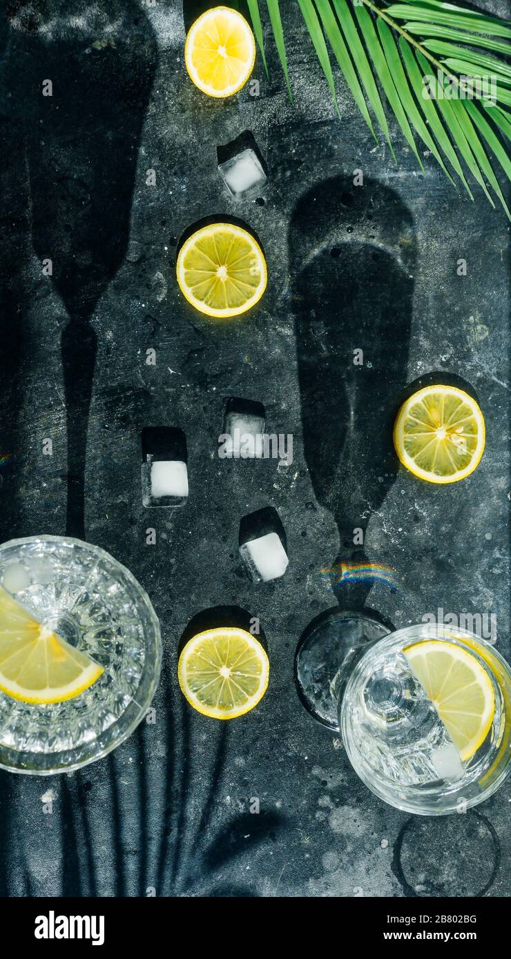 Wasser Zitrone detox. Reines kaltes Wasser mit Zitrone in Kristallgläsern auf dunklem Hintergrund in der sonnigen Sommersonne. Stockfoto